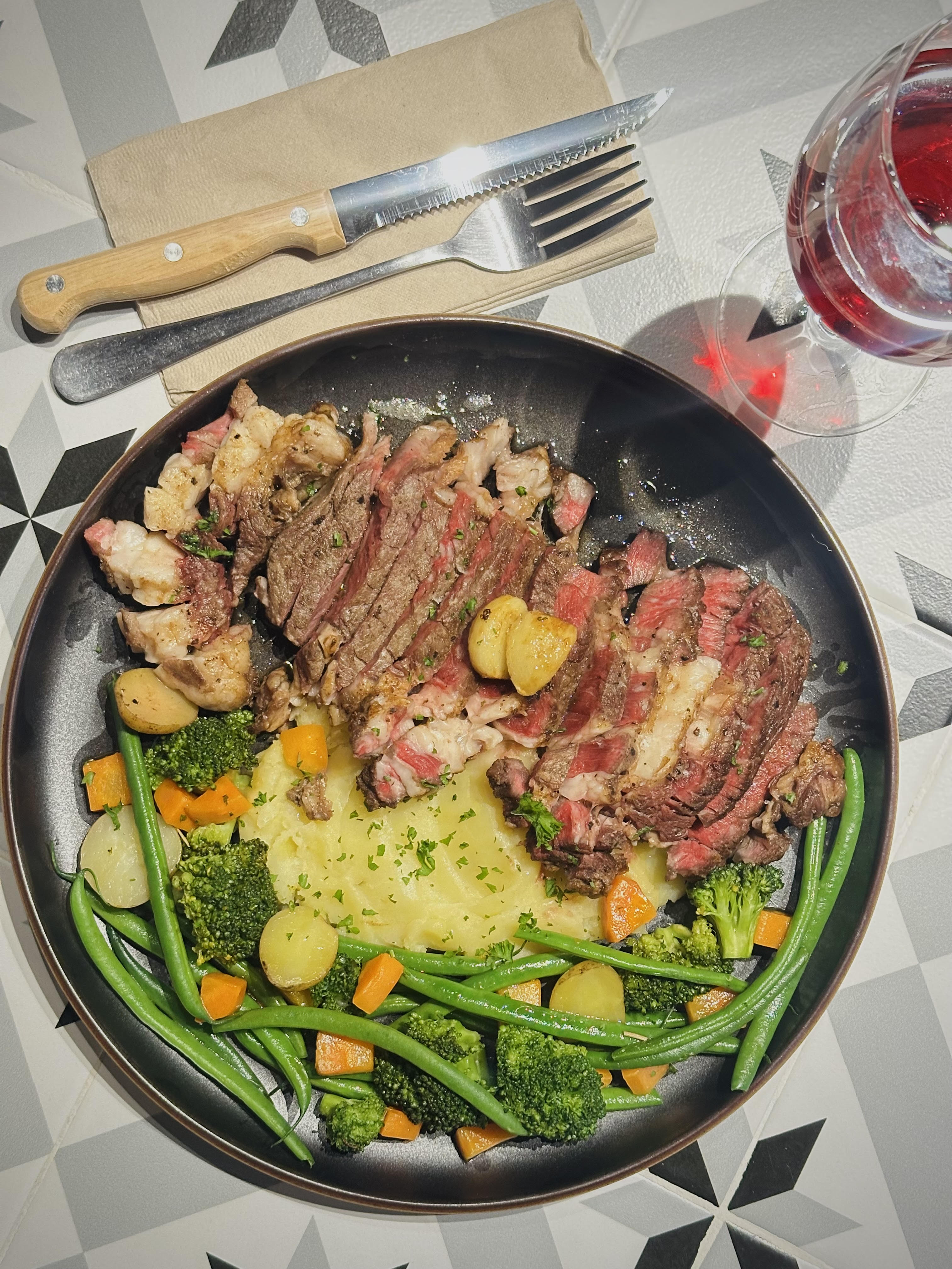 The house entrecôte — seared, sliced and served with garlic confit, buttered mash, vegetables and red wine